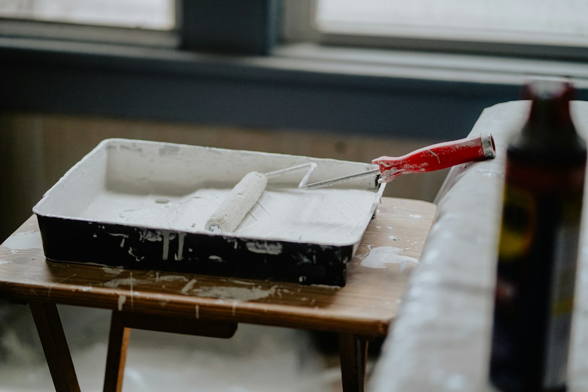 Paint roller in white paint tray — illustrative stock photograph